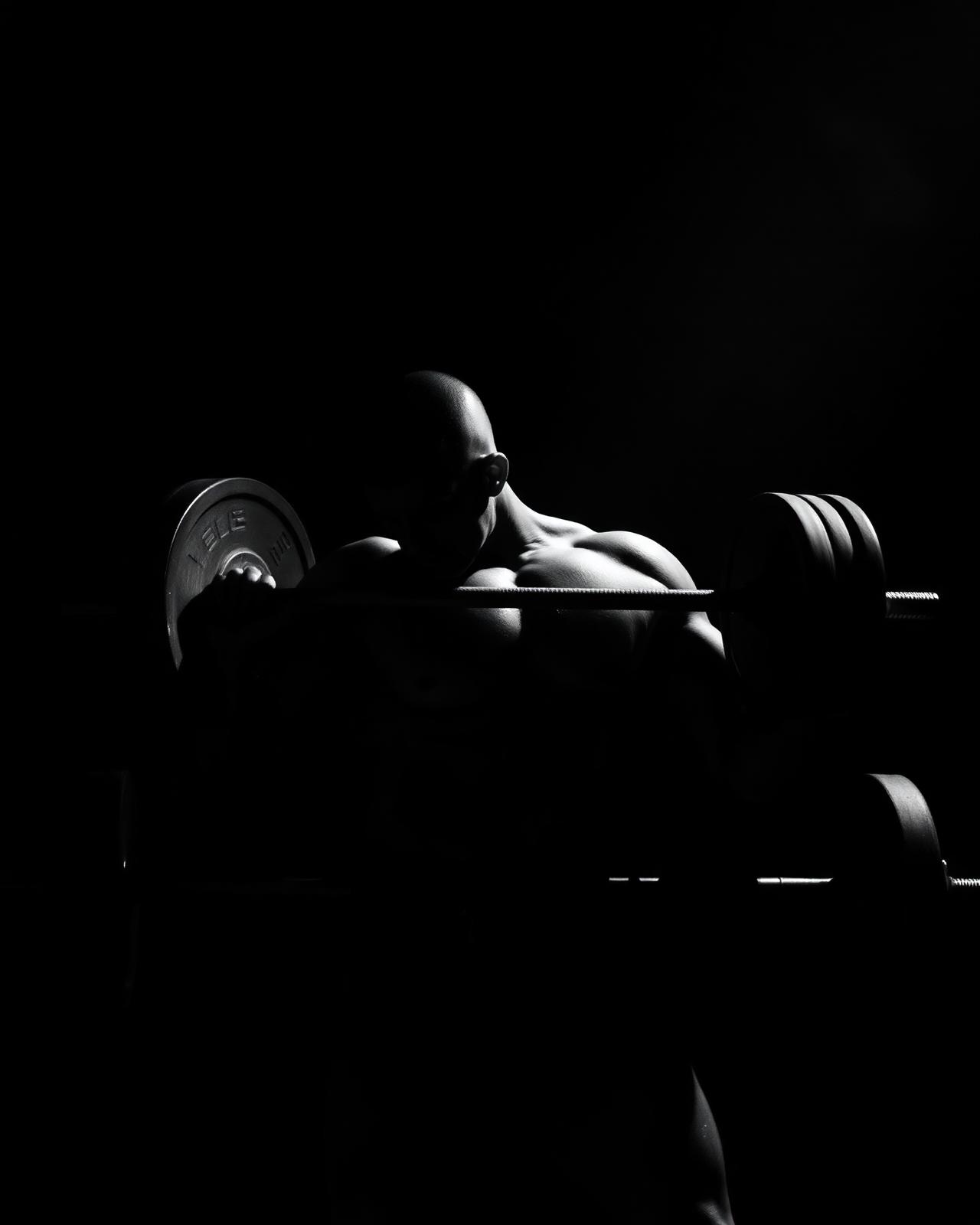 Athlete performing heavy compound lift under contrast lighting